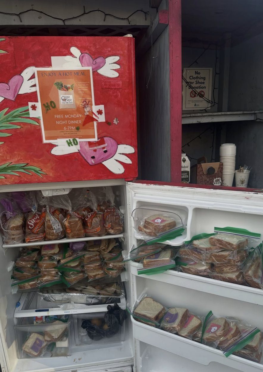 A community fridge stocked with bread and wrapped sandwiches
